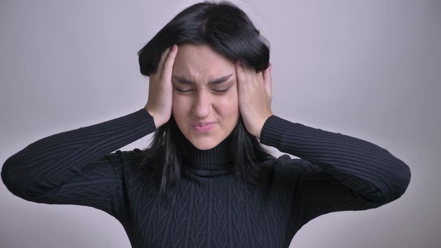 Closeup shoot of young pretty caucasian female overthinking and getting a headache in front of camera