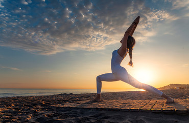 Young girl doing yoga on the beach 