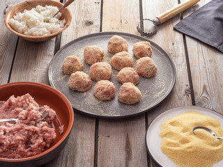 Meatballs cooked for frying and ingredients for cooking meatballs on the old wooden board table