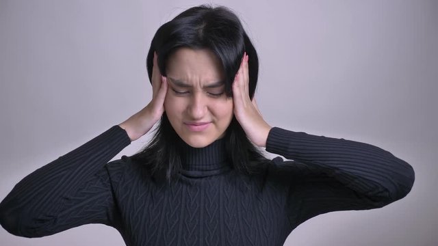 Closeup shoot of young pretty caucasian female overthinking and getting a headache in front of the camera