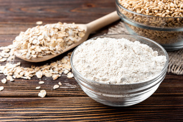 Rolled oats, oat and flour on dark wooden background.