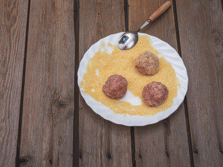 Three raw meatballs are dusted with cornmeal on an old wooden board table, Free space for text.