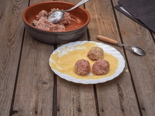 Preparation for cooking meatballs from minced meat. Raw minced meat and cutlery on an old wooden board table.