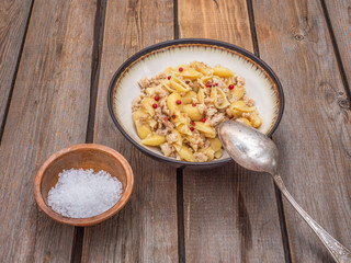 Seashell pasta with turkey minced meat in a deep ceramic plate on the board table