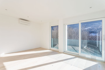 Empty room with white walls and windows overlooking the mountains