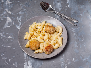 Breakfast of pasta with turkey meatballs in a gray ceramic plate on a gray background