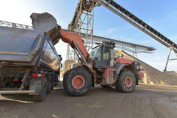 Fototapeta premium Beladen eines LKw´s mit Kies in einem Kieswerk mit einem Radlader // Loading a truck in a gravel plant with a wheel loader