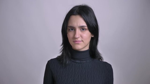 Closeup shoot of young attractive black-haired caucasian female waving her head in token ogf disagreement looking straight at camera