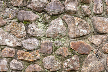 A close up of an old stone wall, with little bits of moss and weeds, perfect for backgrounds and abstracts