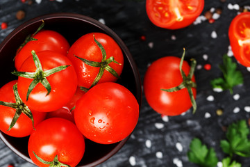 Fresh Sliced Cherry Tomatoes on a black background with spices coarse salt and herbs