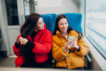 Young females with mobile phone in railway train.