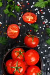 Fresh Sliced Cherry Tomatoes on a black background with spices coarse salt and herbs