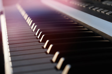 Electronic synthesizer piano keyboard in the sun's rays macro.