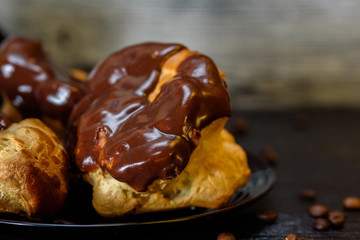 Coffee and chocolate eclairs on a wooden background