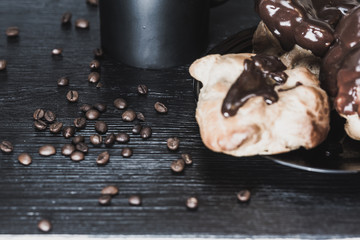 Coffee and chocolate eclairs on a wooden background