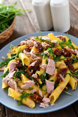 Penne pasta with tuna chunks, rucola and dry tomatoes