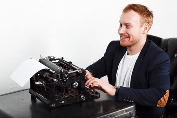 Young man in a suit typing on a typewriter