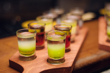 line of alcohol green shots at wooden desk at bar counter