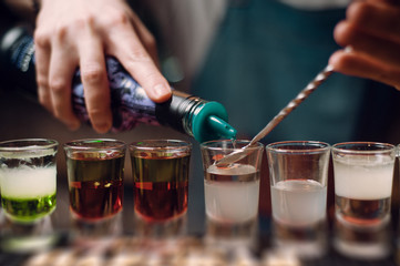 barman pouring shots at a bar counter. barman hands work close up.
