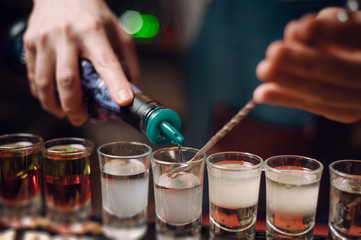 barman pouring shots at a bar counter. barman hands work close up.