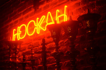 Fototapeta na wymiar line of hookas at red light background. neon hookah sighnboard