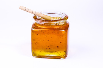 honey in transparent glass jar and wooden honey dipper isolated on white background.