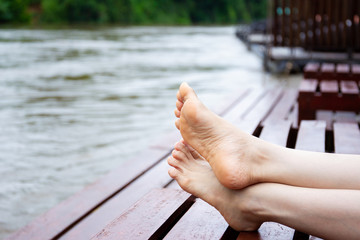 Girl sitting on the wooden bed beside the river.