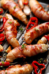 Spicy chicken meat, Grilled chicken tenderloin wrapped with bacon with addition chili peppers, garlic and herbs on grill plate, close-up
