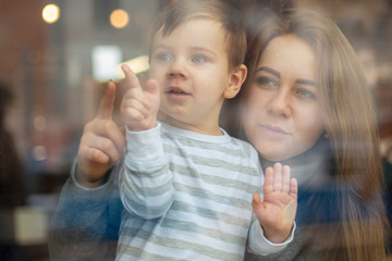 happy family, blonde mother and her beautiful and charismatic little son, the boy is having fun day in a cozy cafe. selective focus, noise effect