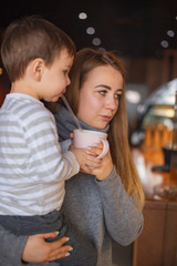 happy family, blonde mother and her beautiful and charismatic little son, the boy is having fun day in a cozy cafe. selective focus, noise effect