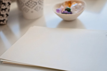 An empty white A4 paper sheet on a table or a desk, healing crystals on a background including: Amethyst Point and Cluster, Agate, Aventurine, Clear Quartz, Citrine, Calcite and Rose quartz.