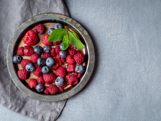 Blueberries and raspberries on plate. A mix of berries on dark background, copy space.