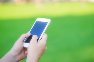 hipster woman using mobile phone touching screen at outdoor, hands typing smart phone texting messaging lifestyle working app device technology internet social data online concept on green background.