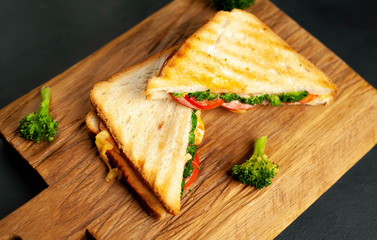 Broccoli cheese sandwiches on wooden cutting board, on concrete, slate background