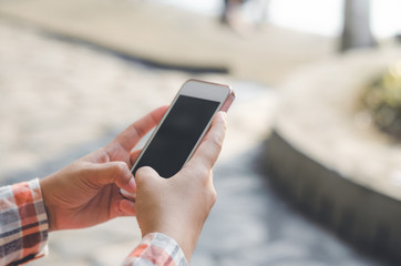 hipster woman using mobile phone touching screen at outdoor with hands typing smart phone texting messaging lifestyle working app device technology internet social data online concept vintage style.