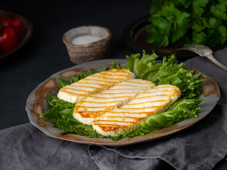 Grilled Halloumi, fried cheese with  lettuce salad.  Balanced diet on  dark background, side view