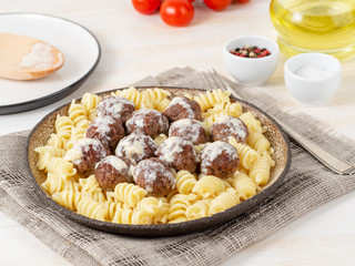 Swedish meatballs with sauce and fusilli paste on white wooden table, side view