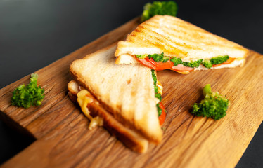 Broccoli cheese sandwiches on wooden cutting board, on concrete, slate background