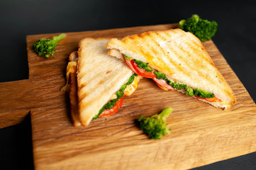Broccoli cheese sandwiches on wooden cutting board, on concrete, slate background