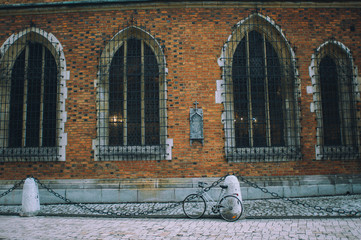 old brick wall of church with two windows and a bicycle