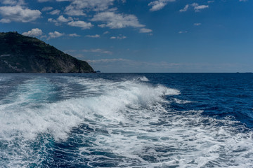 Fototapeta na wymiar Italy, Cinque Terre, Monterosso, a man riding a wave on top of a body of water