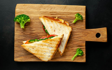 Broccoli cheese sandwiches on wooden cutting board, on concrete, slate background