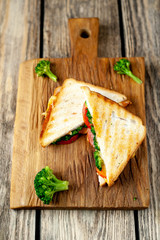 Broccoli cheese sandwiches on wooden cutting board, on wooden table