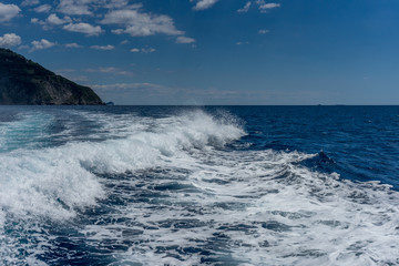 Italy, Cinque Terre, Monterosso, a man riding a wave on top of a body of water