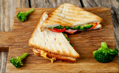 Broccoli cheese sandwiches on wooden cutting board, on wooden table