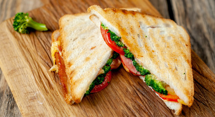 Broccoli cheese sandwiches on wooden cutting board, on wooden table