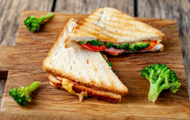 Broccoli cheese sandwiches on wooden cutting board, on wooden table