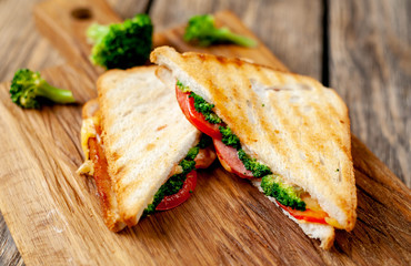 Broccoli cheese sandwiches on wooden cutting board, on wooden table
