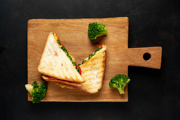 Broccoli cheese sandwiches on wooden cutting board, on wooden table