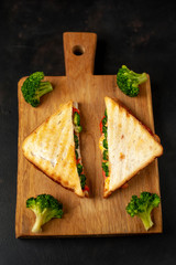 Broccoli cheese sandwiches on wooden cutting board, on wooden table